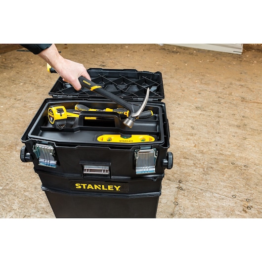 STANLEY 020800R toolbox photography with hand placing hammer inside, showing tape measure and level.