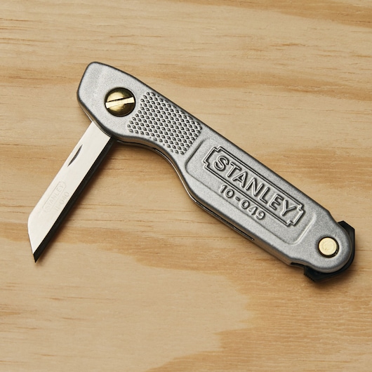 STANLEY 10-049 folding utility knife with silver handle and brass screws on wood surface.
