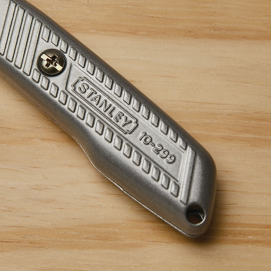 Photo of STANLEY 10-299 utility knife handle, metallic finish, close-up on wooden surface.