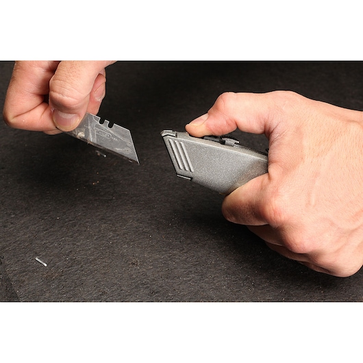 Photo of STANLEY 10-789 utility knife with person changing blade, product held in hand, close-up.