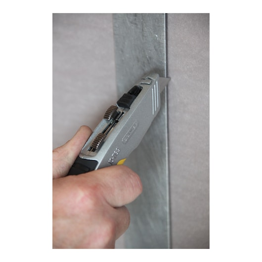 Photo of STANLEY 10-789 utility knife in use cutting drywall panel.