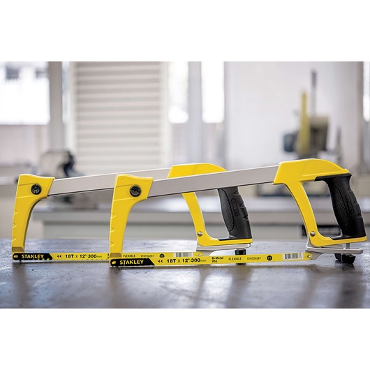 STANLEY 15-098 hacksaw with yellow frame and black handle on a workshop table, side view.