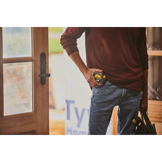 STANLEY 33-425 tape measure held by person wearing jeans, partial indoor setting, photography