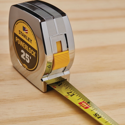 STANLEY PowerLock 25' tape measure SKU 33-425, metal case, yellow blade, angled photo on wood surface.
