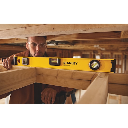 Photo of STANLEY 42-324 I-Beam 180° level tool used on wooden beams at a construction site.
