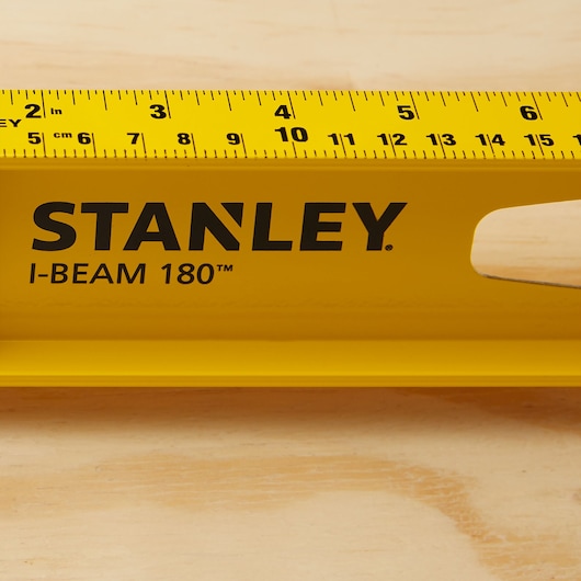 Photo of STANLEY 42-324 I-Beam 180 yellow level tool with imperial and metric scale on wood surface