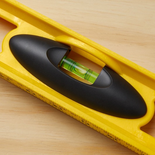 STANLEY 42-468 yellow level tool with black handle, close-up of horizontal vial on wooden surface.