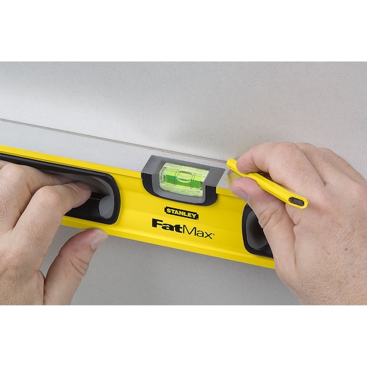 Stanley 43-524 FatMax level tool photography showing hands using pencil on wall.