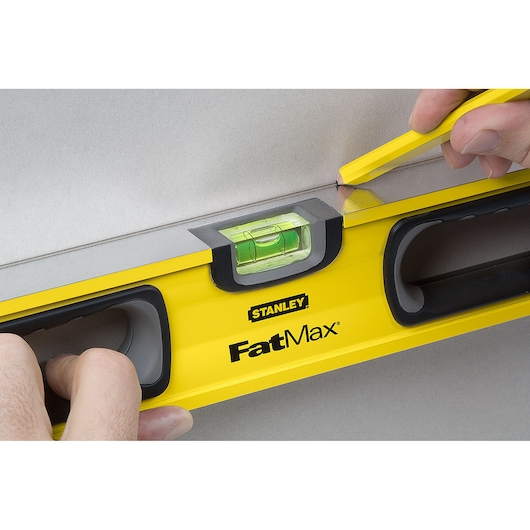 STANLEY 43-524 FatMax level being held and marked with pencil, closeup of yellow tool in use.