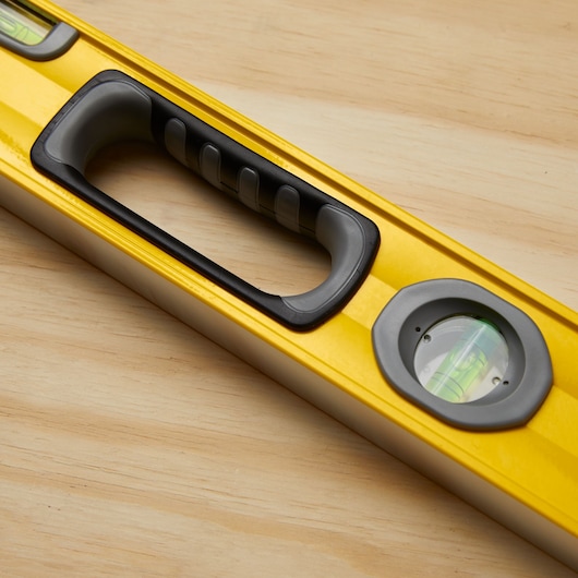 STANLEY 43-524 yellow spirit level with ergonomic handle and vials, close-up on wood surface.