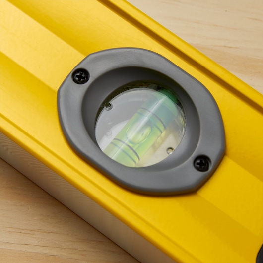 STANLEY 43-572 yellow spirit level close-up showing bubble vial, photographed on wood surface.