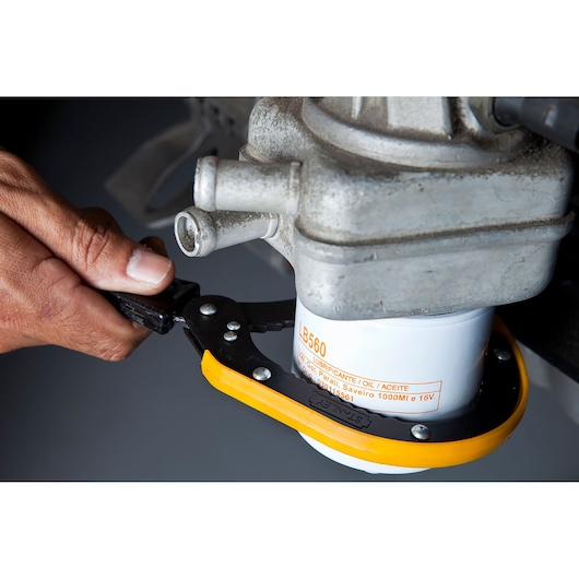 Photo of STANLEY oil filter wrench 78-227 being used to loosen an oil filter. Close-up side angle.