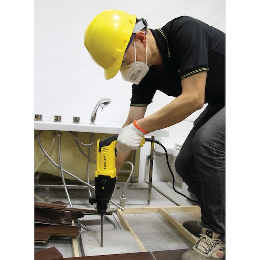 STANLEY SHR263K-BR rotary hammer used to drill floor near sink in construction setting.