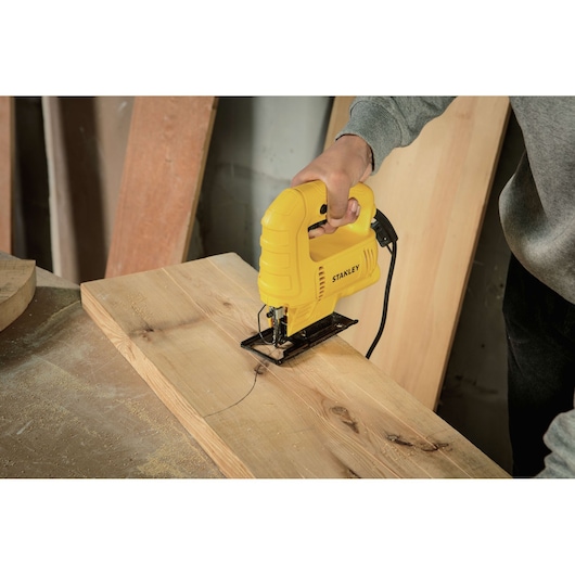 STANLEY SJ45 jigsaw in use cutting a curved line on a wooden board in a workshop.