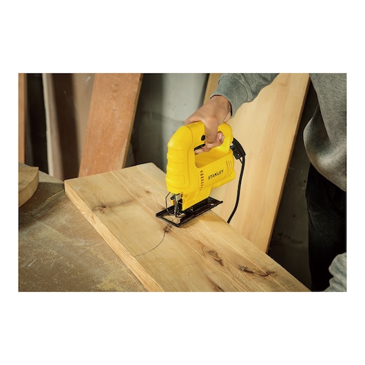 STANLEY SJ45 jigsaw cutting curved line on wooden plank, close-up of tool in use.