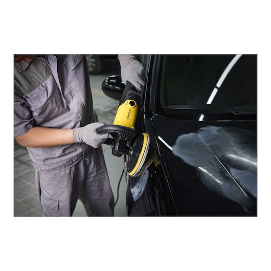 STANLEY SP137 yellow car polisher in use, close-up showing polishing of black vehicle hood.