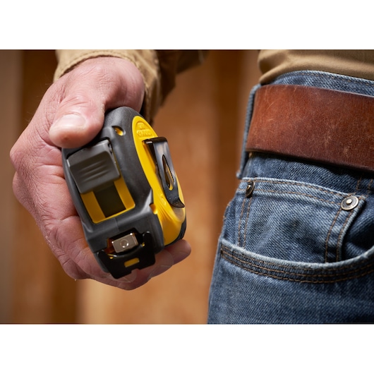 STANLEY STHT37236-5 tape measure held in hand next to blue jeans and brown leather belt.