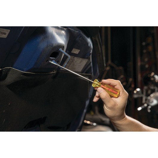 STANLEY STHT69112 screwdriver with yellow handle being used on a car interior bolt, side view.