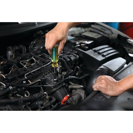 STANLEY STHT69185 screwdriver in use on a car engine, close-up view, yellow handle, automotive repair scene.