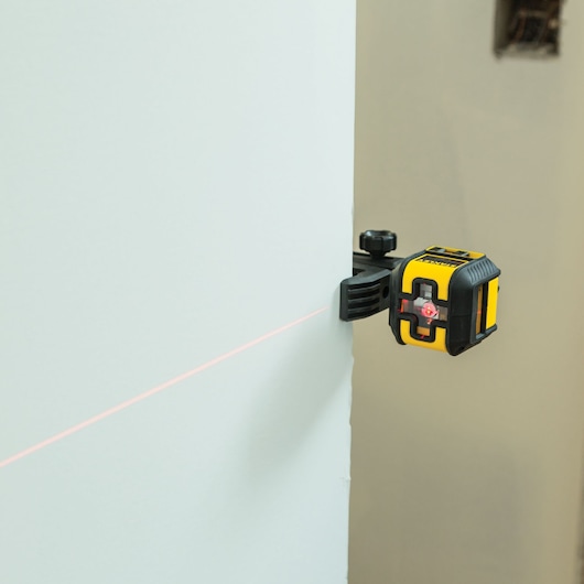 STANLEY STHT77498 laser level tool mounted on wall, emitting a horizontal red laser line.