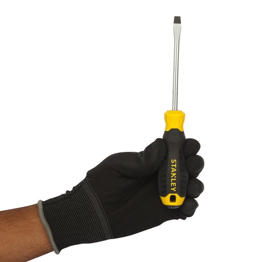 STANLEY STMT60826-8 flathead screwdriver with yellow and black handle held by a gloved hand, front view.