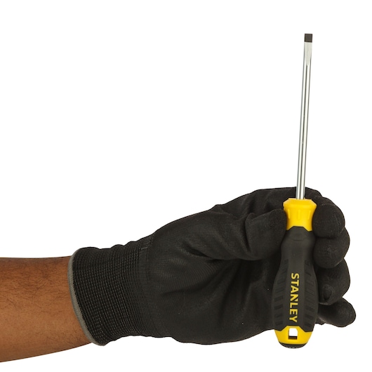 Stanley STMT60834-8 flathead screwdriver with yellow and black handle held by gloved hand, side angle.
