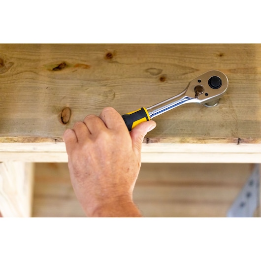 STANLEY STMT82665-0 ratchet hand tool used on wood, close-up of hand holding tool.