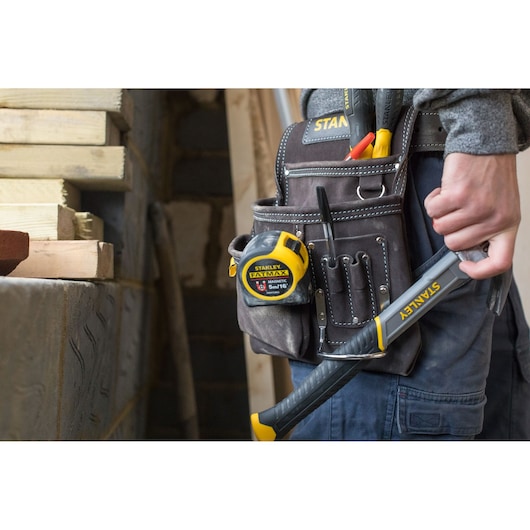 STANLEY STST1-80114 tool belt with tape measure, hand tools, and hammer in use at a construction site.