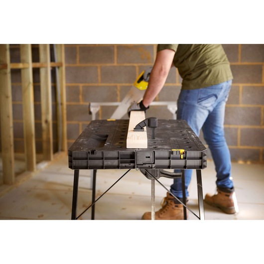STANLEY STST11552 workbench with wood clamped, photo of product in use in construction setting.