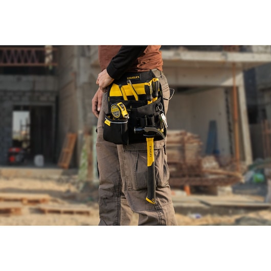Photo of STANLEY STST511324LA tool belt with tools, worn at a construction site, black and yellow design.